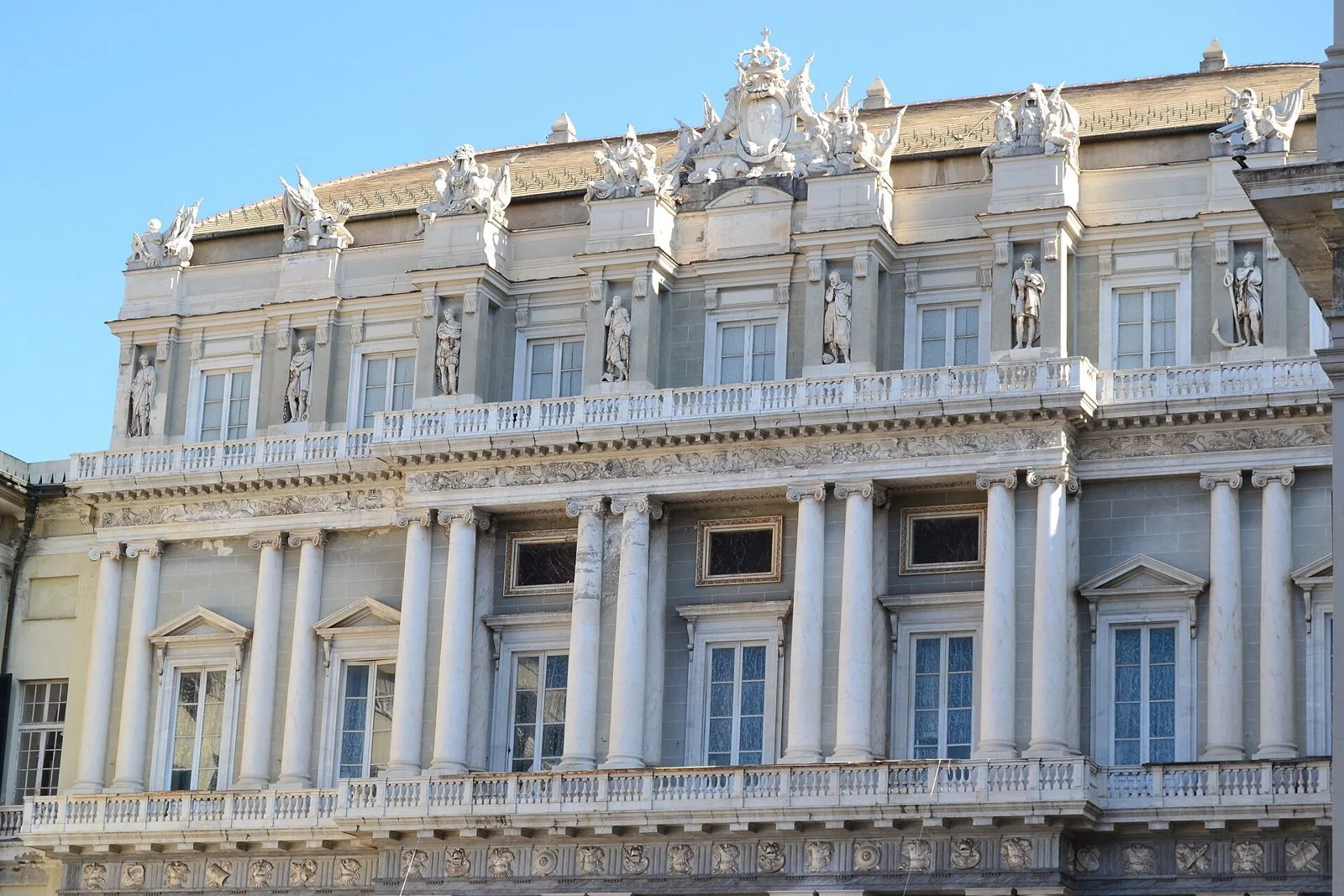 La facciata neoclassica di Palazzo Ducale su piazza Matteotti, con colonne bianche, balconate e statue sotto un cielo azzurro